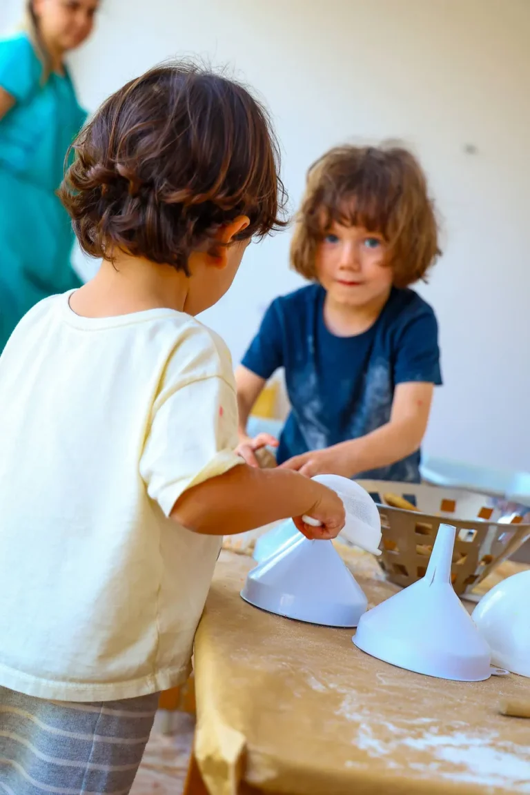 Duas crianças compartilham uma exploração com utensílios e materiais na Sabiá.