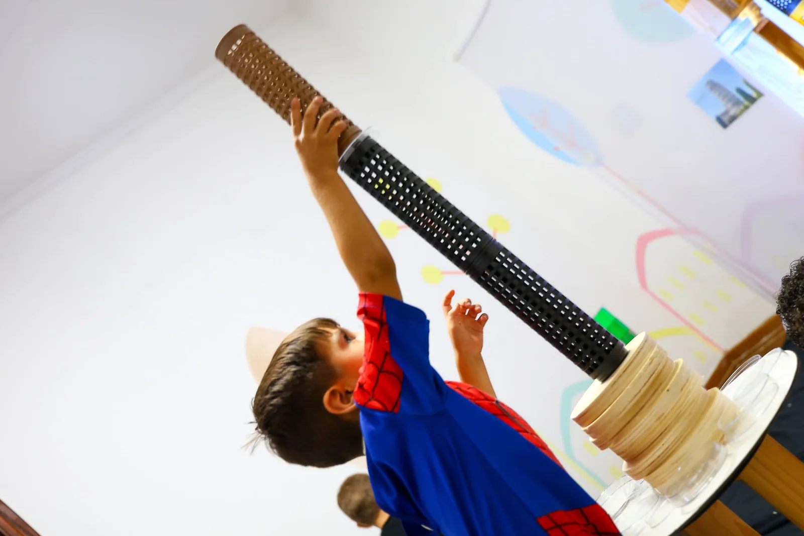 Criança levanta uma construção com materiais de diferentes tamanhos.