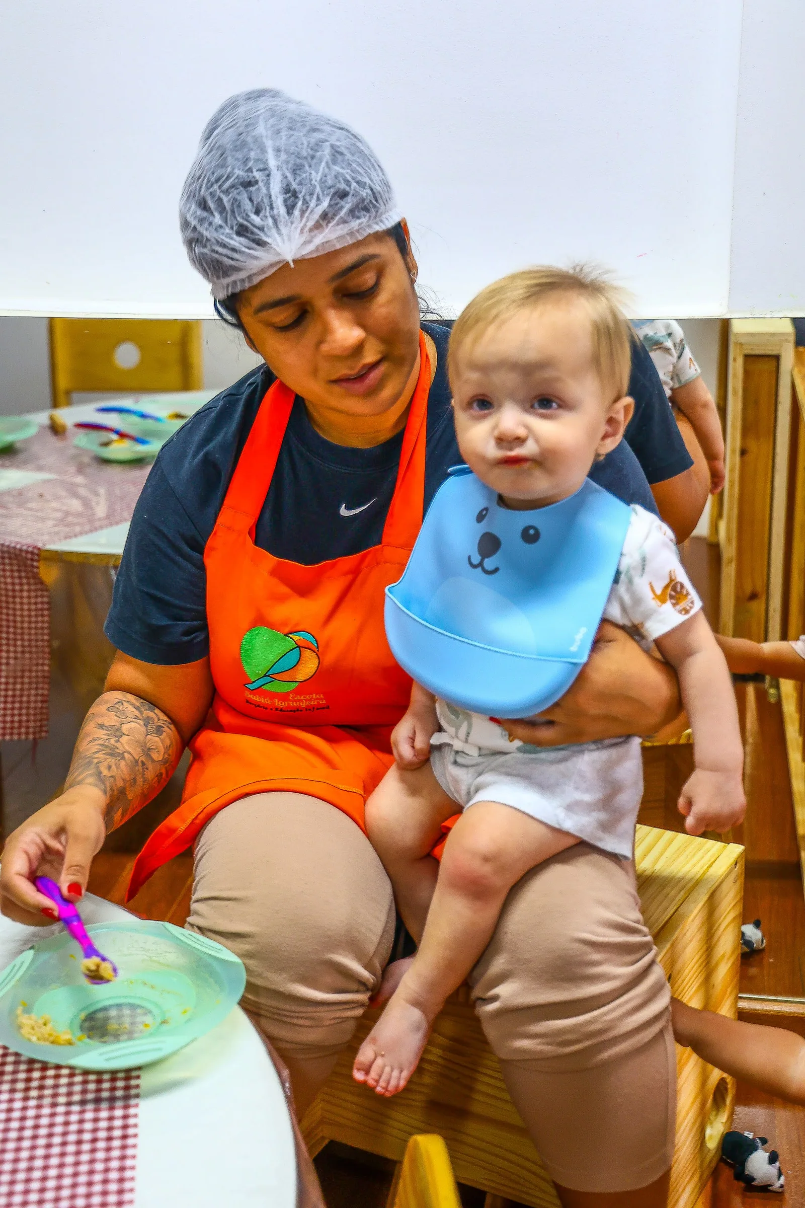Educadora acompanha um bebê em um momento do cotidiano da escola.