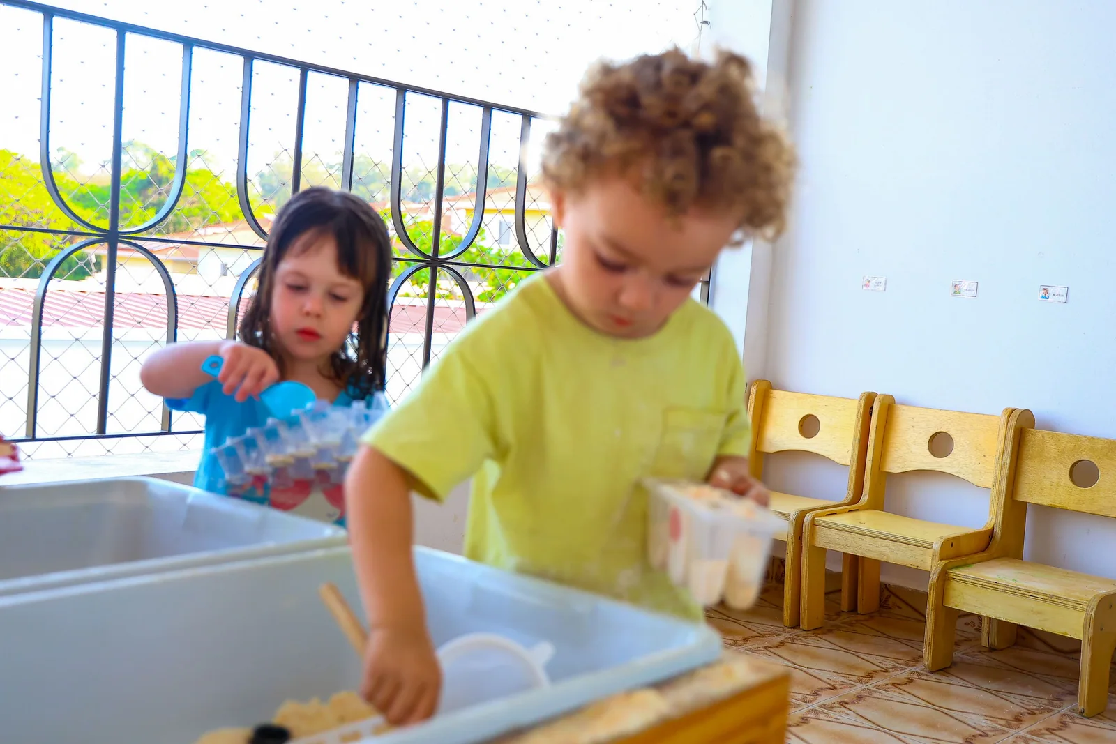 Crianças investigam materiais e recipientes durante uma brincadeira.
